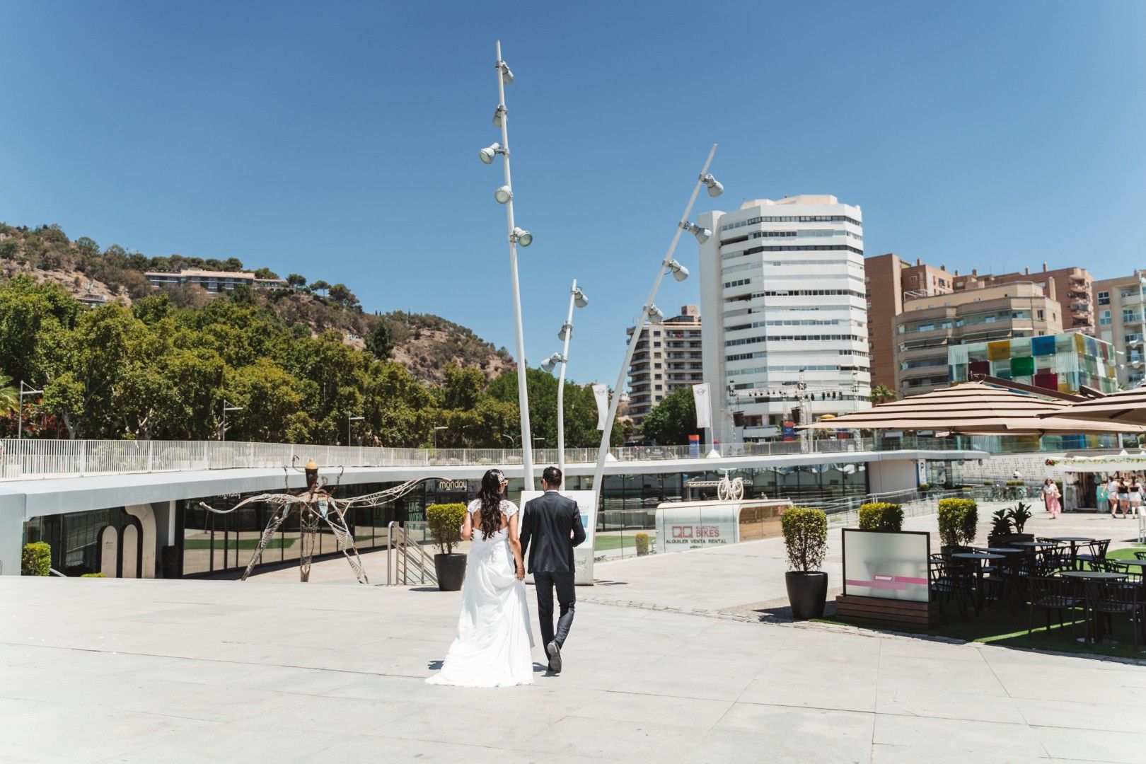 Bride and groom holding champagne glasses during their wedding day in a sunlit garden in southern Spain
