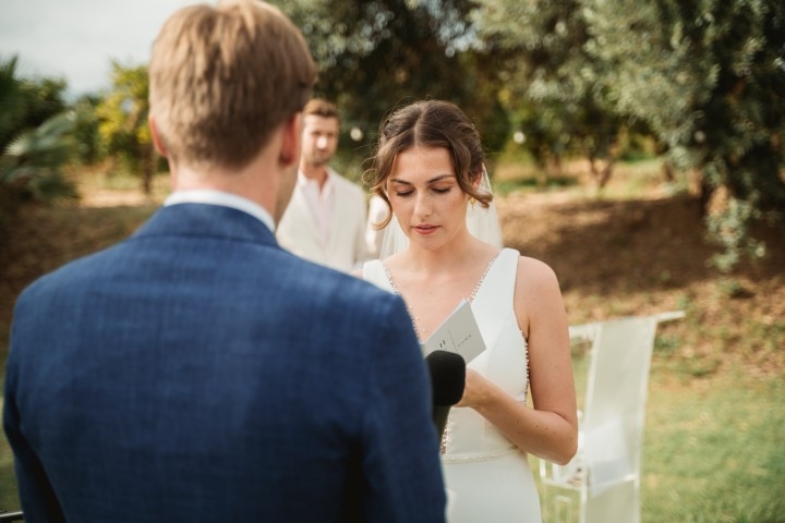 Bride reading her vows during an outdoor wedding ceremony in soft natural light