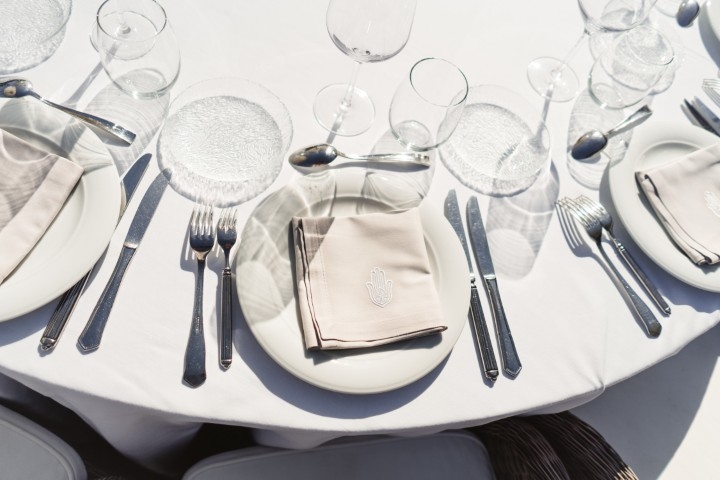 Elegant white wedding table setting with glassware and folded napkins in bright natural light