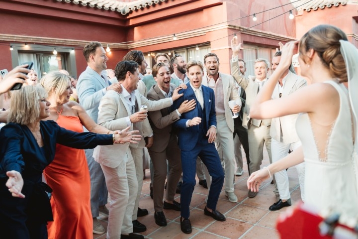 Wedding guests laughing and dancing during an outdoor reception in a Spanish courtyard