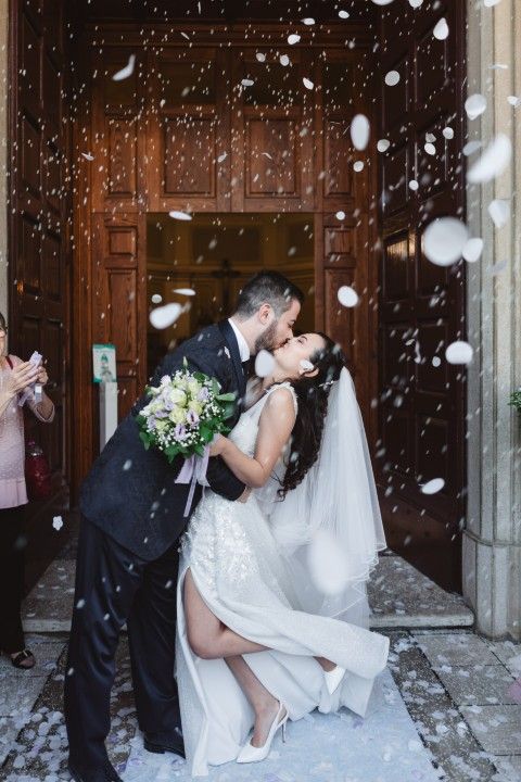 Newly married couple kissing under a shower of confetti as they leave the ceremony