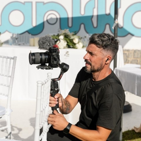 Wedding videographer filming discreetly with a handheld camera during a ceremony in Spain
