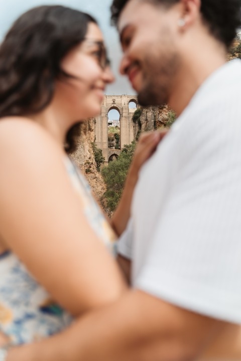 Couple in soft focus with Puente Nuevo in Ronda framed sharply in the background