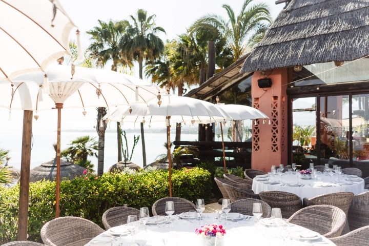 Guests mingling during cocktail hour at a Marbella wedding venue with palm trees and garden setting