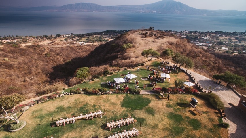 Aerial view of a destination wedding venue and reception setting overlooking the water during a wedding celebration